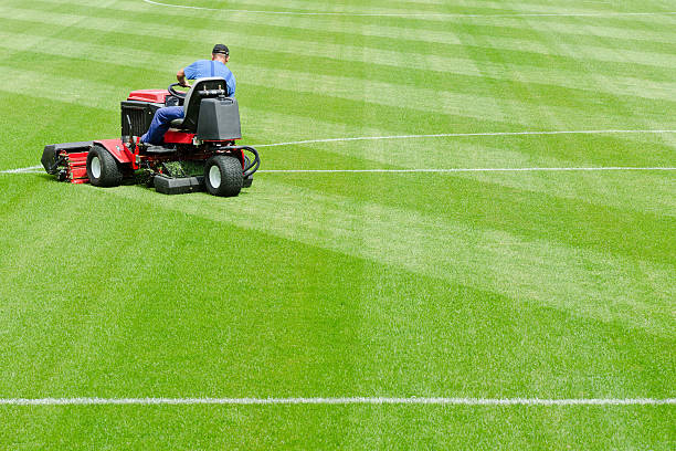 A man mowing the grass on a football stadium